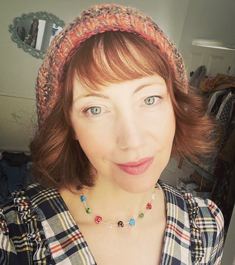 white woman in knit hat and bead necklace