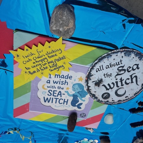 Close up of the shiny blue table with lots of colourful paper and signs about the Sea witch